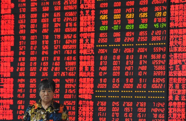 2014年9月12日 在中国东部安徽省阜阳市一家股票经纪公司 一名中国投资者走过显示股价 价格上涨为红色 价格下跌为绿色 的屏幕 — 图库照片