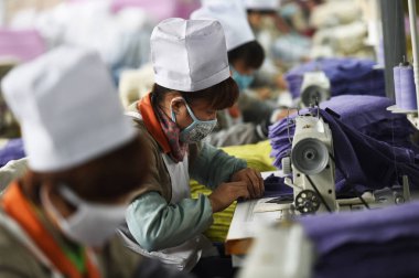 Female Chinese workers sew clothes to be exported to the United States at a garment factory in Zouping county, east China's Shandong province, 16 November 2014 clipart