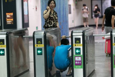A Chinese passenger worms his way through a turnstile at the Xizang Road S. Metro station in Shanghai, China, 12 August 2013 clipart