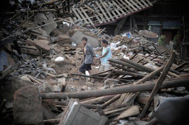 Villagers walk past the debris of collapsed houses after the 6.5-magnitude earthquake in Longquan village, Longtoushan town, Ludian county, Zhaotong city, southwest Chinas Yunnan province, 5 August 2014 clipart