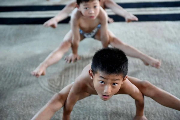 中国日报 的报道 2014年7月9日 中国东部安徽省博州市某体操培训中心的一名年轻男孩为了保持身体平衡 双手放在地板上练习体操 — 图库照片