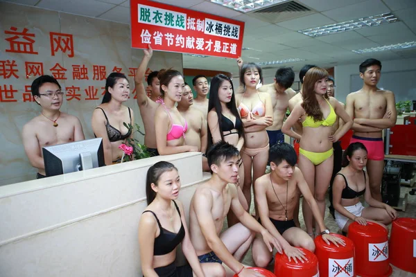 stock image Chinese employees dressed in bikinis and swimming trunks pose behind empty buckets to boycott the Ice Bucket Challenge at their office in Shenzhen city, south China's Guangdong province, 26 August 2014