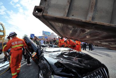 Chinese firefighters try to rescue a driver and another passenger out of an Audi S5 crushed and flattened by an overturned container on the 324 National Highway in Quanzhou city, southeast Chinas Fujian province, 28 October 2013 clipart