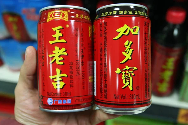 2013年12月20日 上海のスーパーマーケットで JiaduobaoグループのJiaduobaoハーブティーの缶と 広州製薬ホールディングスのウォン カトハーブティーの缶を取り出す中国人客が 中国の顧客に店を組む — ストック写真