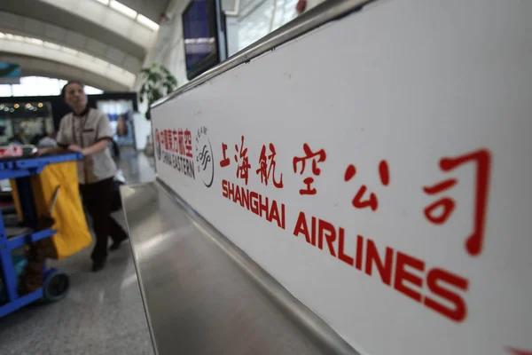 ファイル 中国人労働者が中国中部湖北省武漢の空港で上海航空の看板を通り過ぎる 2013年5月9日 — ストック写真