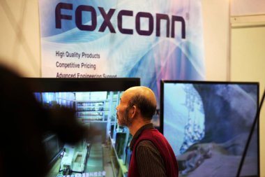 A visitor walks past the stand of Foxconn during the 11th Electronics Manufacturing Exhibition (eMEX Suzhou) in Suzhou, east Chinas Jiangsu province, 19 October 2012.