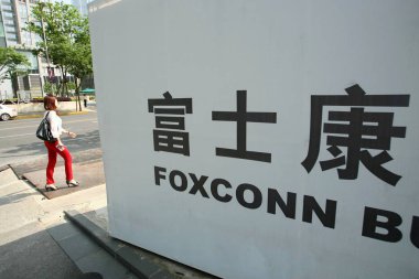 --FILE--A pedestrian walks past a signboard of the Foxconn Building in the Lujiazui Financial District in Pudong, Shanghai, China, 11 May 2012 clipart