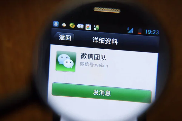 中国の携帯電話ユーザーは 2013年7月22日にスマートフォンでテンセントのメッセージングアプリWeixin またはWechatを使用しています — ストック写真
