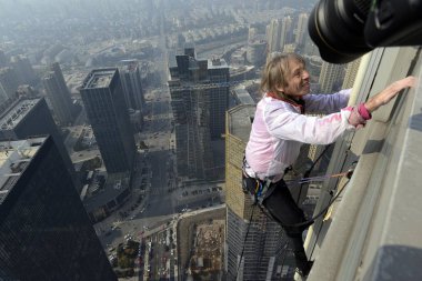 French Spiderman Alain Robert is climbing the 288-meter-tall Shimao Horizon Center Building in Shaoxing city, east Chinas Zhejiang province, 21 December 2013 clipart
