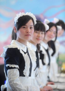 Waitresses, dressed as maids, set a table at a cosplay restaurant in Yangzhou city, east Chinas Jiangsu province, 5 February 2012 clipart