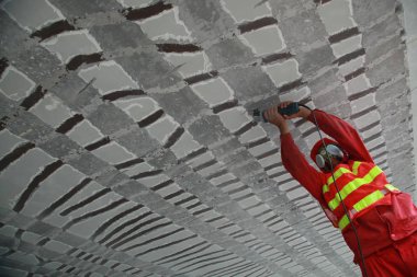 A Chinese worker polishes and repairs the cracks on the bottom of a section of Nanda Viaduct in Haikou city, south Chinas Hainan province, 8 August 2013 clipart