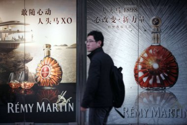 A pedestrian walks past advertisements for Remy Martin cognac of Remy Cointreau at a shopping mall in Shanghai, China, 4 March 2013 clipart