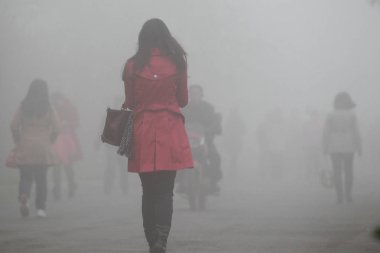 Pedestrians walk on a street in heavy smog in Shenyang city, northeast Chinas Liaoning province, 21 October 2013 clipart