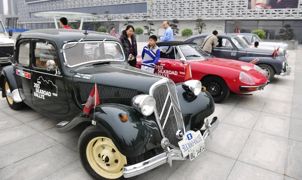 訪問者は 2013年10月20日 中国河南省中部のルオヤンにある泉春ショッピングプラザでの展示会で 2013年シルクロードラリーを達成したシトロエンやその他のブランドの古いタイマーカーを見ます — ストック写真