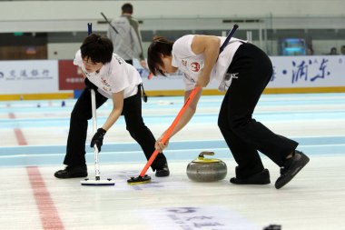 Michiko Tomabechi of Japan, left, and Kaho Onodera sweep in the womens semifinal match against China during the Pacific-Asia Curling Championships 2013 in Shanghai, China, 18 November 2013. clipart