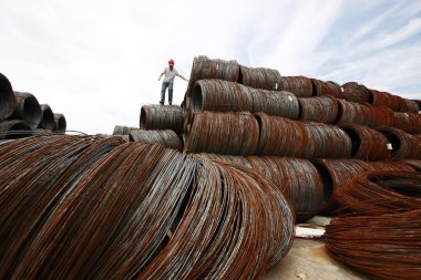 A Chinese worker stands on rolls of coiled steel rods at a steel processing plant in Huaibei, east Chinas Anhui province, 30 July 2013 clipart