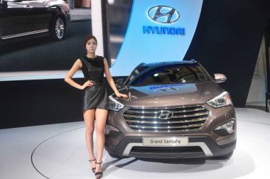 A model poses with a Hyundai Grand SantaFe at the stand of Hyundai during the 15th Shanghai International Automobile Industry Exhibition, known as Auto Shanghai 2013, in Shanghai, China, 29 April 2013 clipart