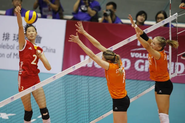 女性の中国のバレーボール選手は 中国はマカオでバレーボール世界グランプリマカオ2013でオランダ3 を打つ試合中にディフェンダーに対してボールを打つ 月2013 — ストック写真