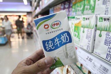 A customer buys a carton of Yili pure milk at a supermarket in Xuchang, central Chinas Henan province, 22 June 2013 clipart
