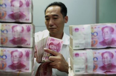 A Chinese employee counts RMB (renminbi) yuan notes at a bank in Huaibei, central Chinas Anhui province, 6 November 2013 clipart