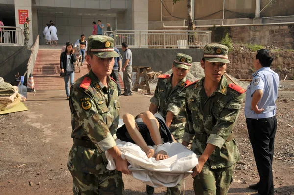 stock image Chinese soldiers carry a patient on a stretcher out of the Peoples Hospital after it was partially destroyed by a landslide in Yiliang county, southwest Chinas Yunnan province, 26 August 2013