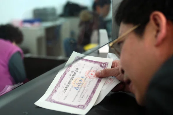 市民は 中国のペイセンターのホールでナンバープレートの証明書を示しています 2012年3月19日 — ストック写真