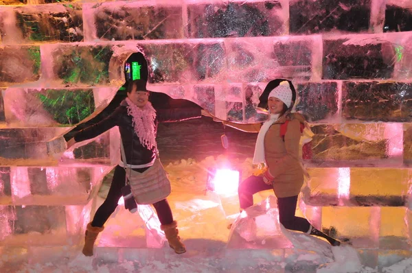 2013年12月26日 在中国东北黑龙江省哈尔滨市举行的第40届哈尔滨冰灯艺术博览会试运行期间 参观者在冰雕的空心中摆姿势拍照 — 图库照片
