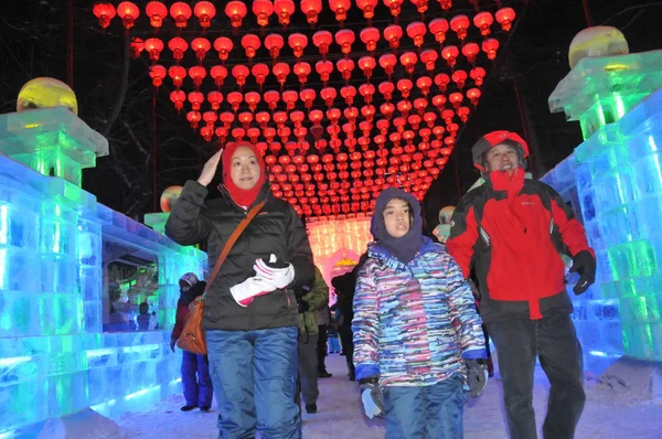 2013年12月26日 在黑龙江省东北部哈尔滨市举行的第40届哈尔滨冰灯艺术博览会试制期间 游客在红灯笼下走过冰雕 — 图库照片