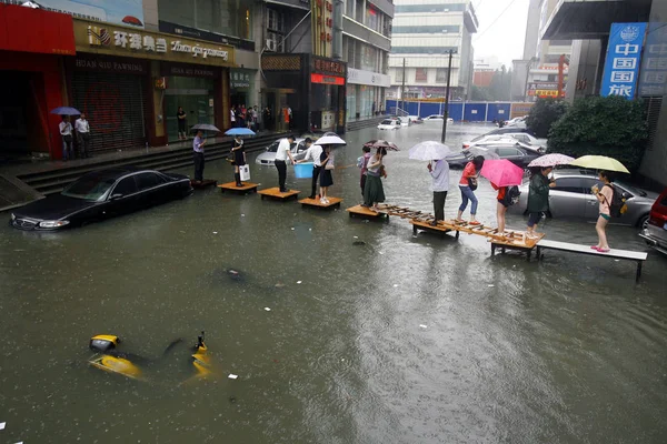 歩行者は 中国湖北省中央部 武漢市の豪雨で浸水した通りを横断するために机を通って歩き 月2012 — ストック写真