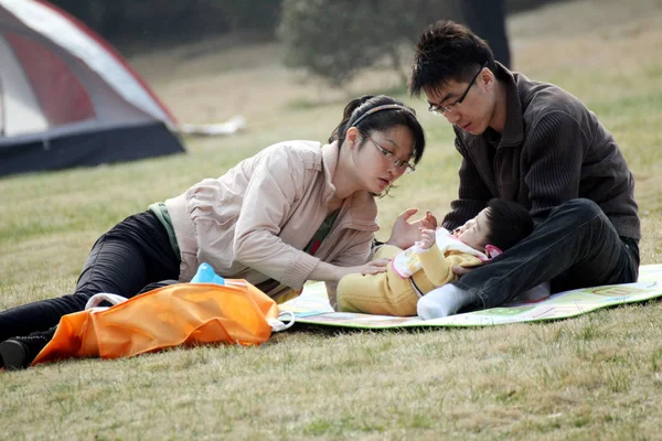2012年4月8日 在中国东部山东省青岛市 一对年轻的中国夫妇在草坪上照顾孩子 — 图库照片