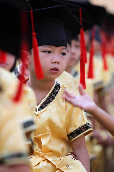 伝統的な衣装を身にまとった若い中国人学生は ジンジャン市の Gaoxia 小学校での孔子誕生の2563Rd 周年を記念して 最初の筆記式に参加しました Provinc — ストック写真