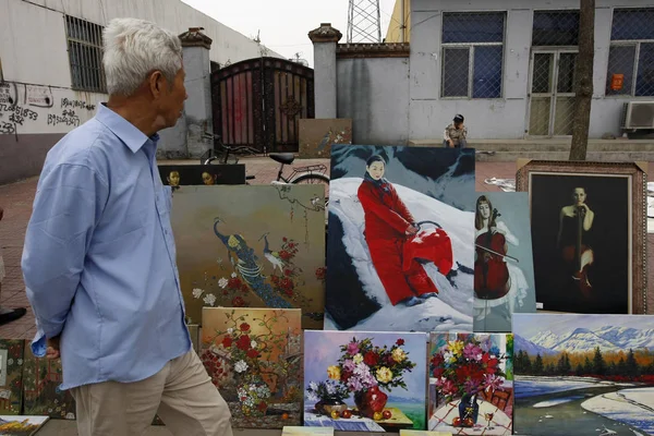 2009年9月19日 北京市通州区宋庄艺术家村宋庄第五届文化艺术节上 一位中国老人走过一条街的摊位出售画作 — 图库照片