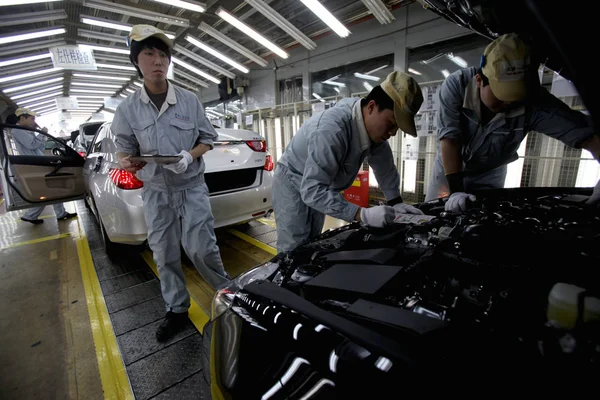 中国の労働者は 2012年3月23日 中国天津のトヨタの自動車工場で組み立てライン上のトヨタ車をチェックします — ストック写真