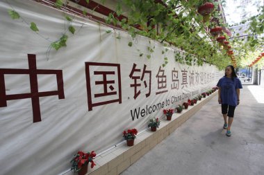A staff member walks past a banner with signs saying, Welcome to China Diaoyu Islands, at Diaoyu Islands Hotel in XiAn city, northwest Chinas Shaanxi province, 14 September 2012 clipart