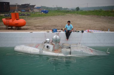 Zhang Wuyi, a laid-off worker who builds mini submarines in his workshop, sits on the bank before a test for the finished submarine in Wuhan, central Chinas Hubei province, 7 May 2012 clipart