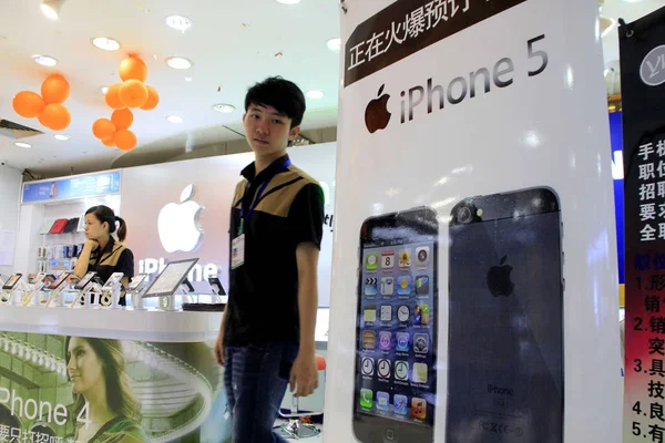 2012年9月14日 在中国海南省海口市的一家手机商店 一名中国员工走过一张苹果Iphone 5智能手机预订海报 — 图库照片