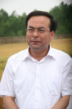 --FILE--Sun Zhengcai, Minister of Agriculture, looks at a wheat field during his visit to an agricultural science and technology testing base in Mengcheng county, Bozhou city, east Chinas Anhui province, 27 May 2008 clipart