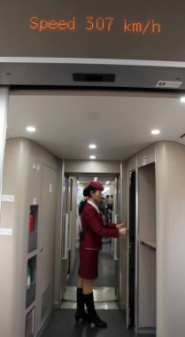 A Chinese attendant walks under a display showing the speed aboard a CRH (China Railway High-speed) bullet train running on the Beijing-Guangzhou High-speed Railway in China, 22 December 2012 clipart