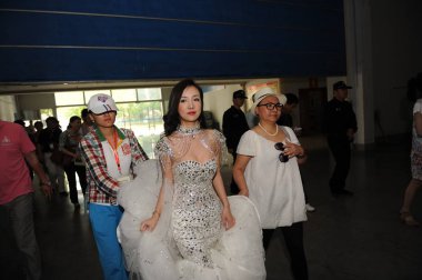 Chinese model Gan Lulu, center, and her mother Lei Bingxia, right, arrive for an auto show in Weifang city, east Chinas Shandong province, 25 May 2012 clipart