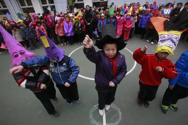 中国山東省済南市の幼稚園で2012年12月19日に行われたクリスマスを祝う環境保護キャンペーンでは 廃棄物で作られた帽子を身に着けている若い中国の子供たちが江南スタイルのダンスを行います — ストック写真