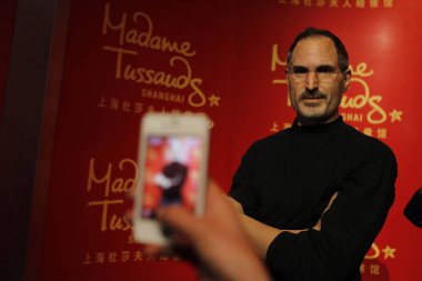 A visitor uses an iPhone 4S smartphone to take photos of the wax figure of Steve Jobs at Madame Tussauds in Shanghai, China, 24 December 2012 clipart