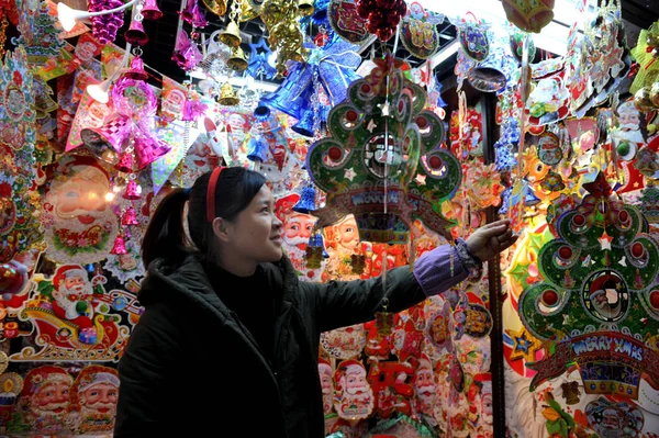 中国のベンダーは 2012年12月18日 中国浙江省東部のYiwu市のYiwu国際貿易都市の店で販売のためのクリスマスの飾りをハングアップします — ストック写真