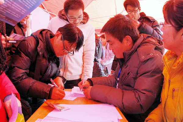 中国の大学卒業生は 2011年2月14日 中国中部河北省志家荘市の就職フェアでブースにフォームを記入します — ストック写真