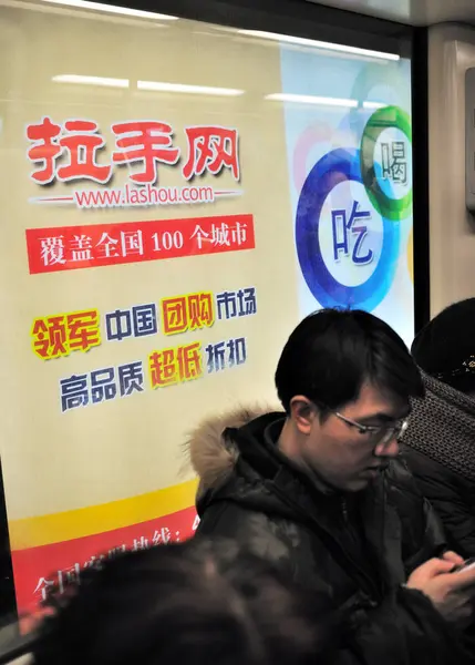 中国の乗客は 2011 上海に Lashou Com のサイト オンライン グループの購買の広告の前に地下鉄の電車の中描かれて — ストック写真