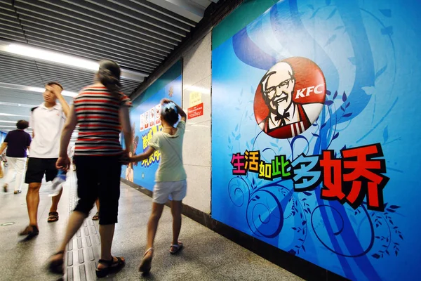 中国の北京にある地下鉄の駅で Kfc のための広告を通り過ぎた地元の中国人が 8月1日2010 — ストック写真