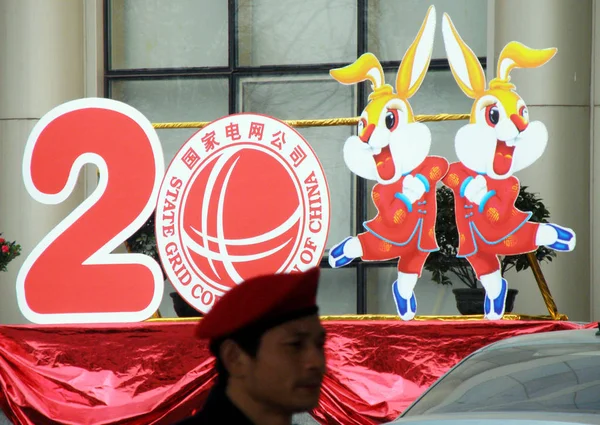 中国国家电网公司分公司 一名中国安保人员在展示的2011年兔为主题的标志前站岗 以庆祝即将到来的春节 也称为中国农历新年或兔年 — 图库照片