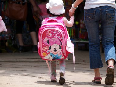 A Chinese kid carrying a big schoolbag on the back is escorted by her parent to her kindergarten on the first day of her new semester in Anze county, Linfen city, northwest Chinas Shanxi province, 1 September 2011 clipart