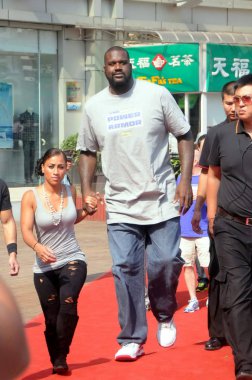 Former NBA superstar Shaquille ONeal and his girlfriend Nicole Hoopz Alexander attend a promotional event by Chinese sportswear brand Li-Ning during his China tour in Nanning city, south Chinas Guangxi Zhuang Autonomous Region, 19 October 2011. clipart