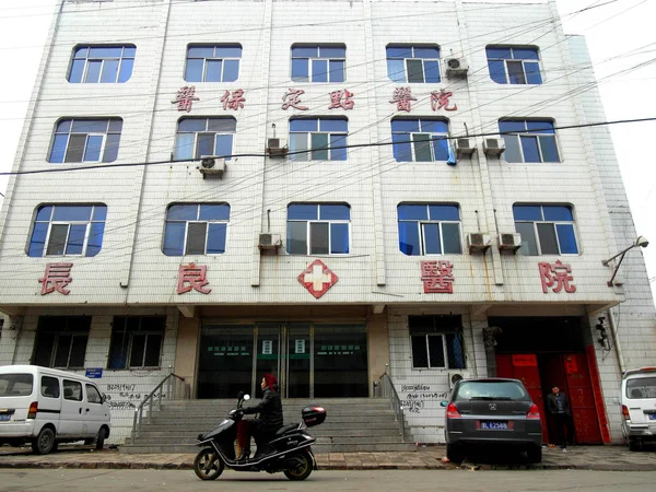 中国のサイクリストは 2011年4月6日 中国北西部山西省リンフェン市の違法腎臓移植で閉鎖された長江病院を通り過ぎる — ストック写真