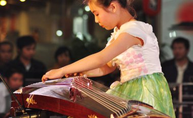 A Chinese kid plays Guzheng, or Chinese zither, during a kid talent competition in Suzhou city, east Chinas Jiangsu province, 4 December 2010. clipart